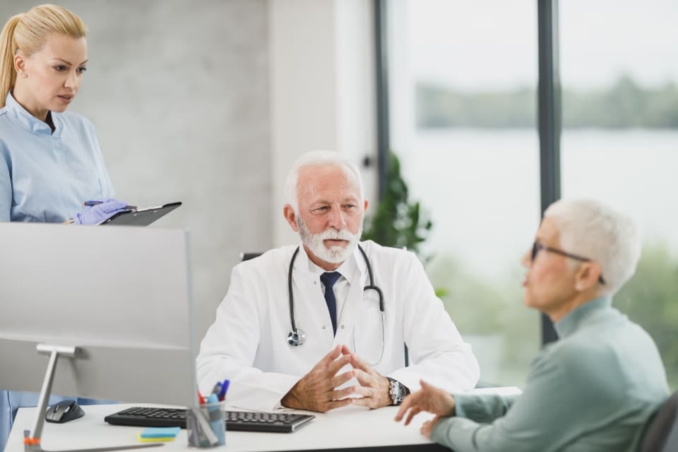 Arzt im Gespräch mit einer Patientin am Schreibtisch