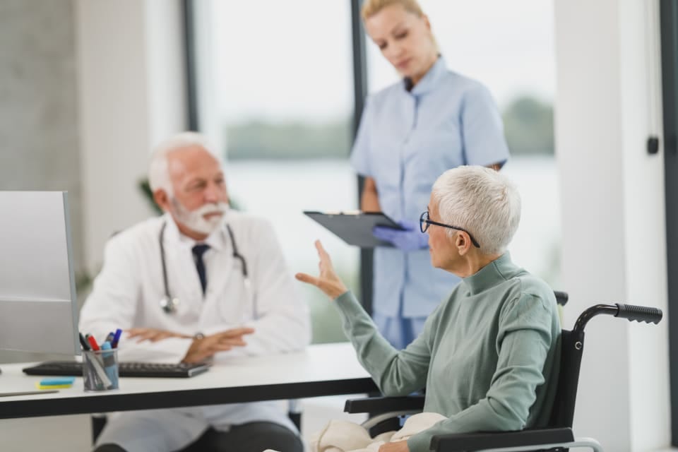Hausarzt mit Patientin und Praxismitarbeiterin