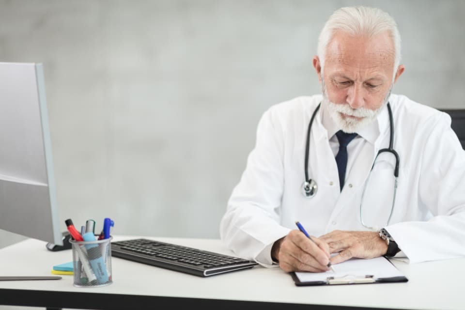 Arzt schreibt Notizen in eine Patientenakte