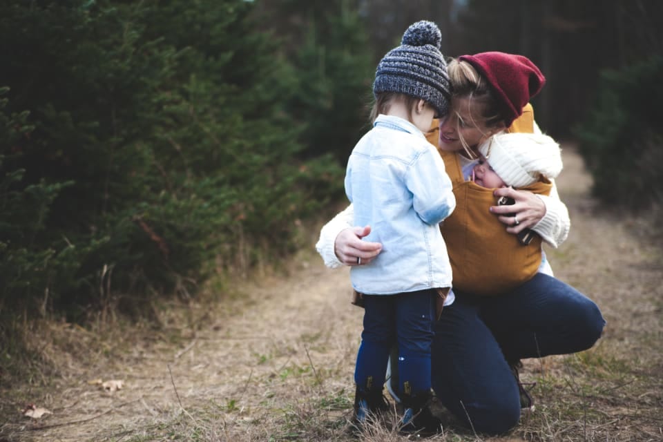 Mutter mit Kleinkind und Baby im Freien