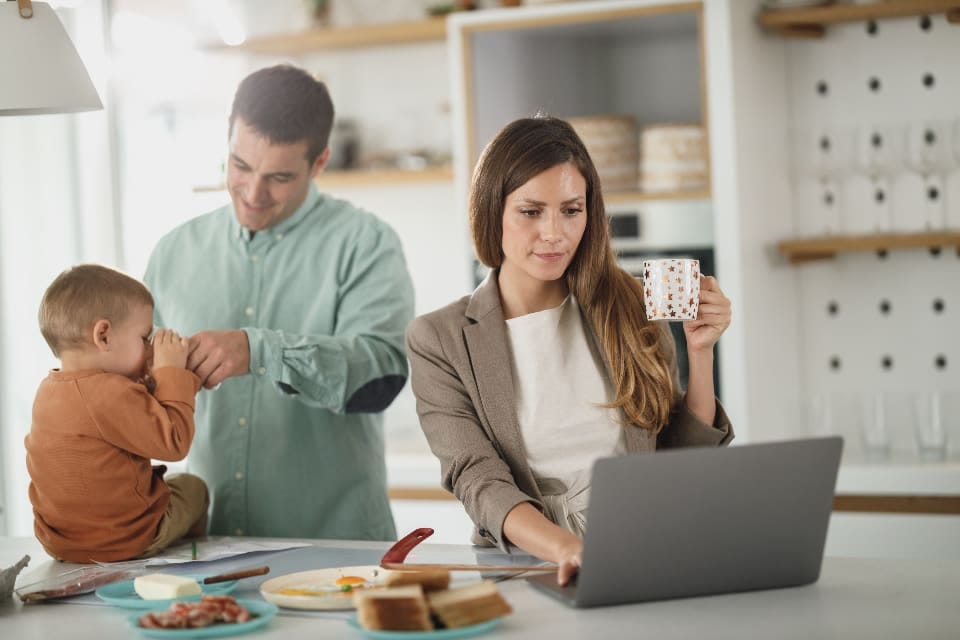Mutter arbeitet am Laptop, der Vater kümmert sich um das Kind