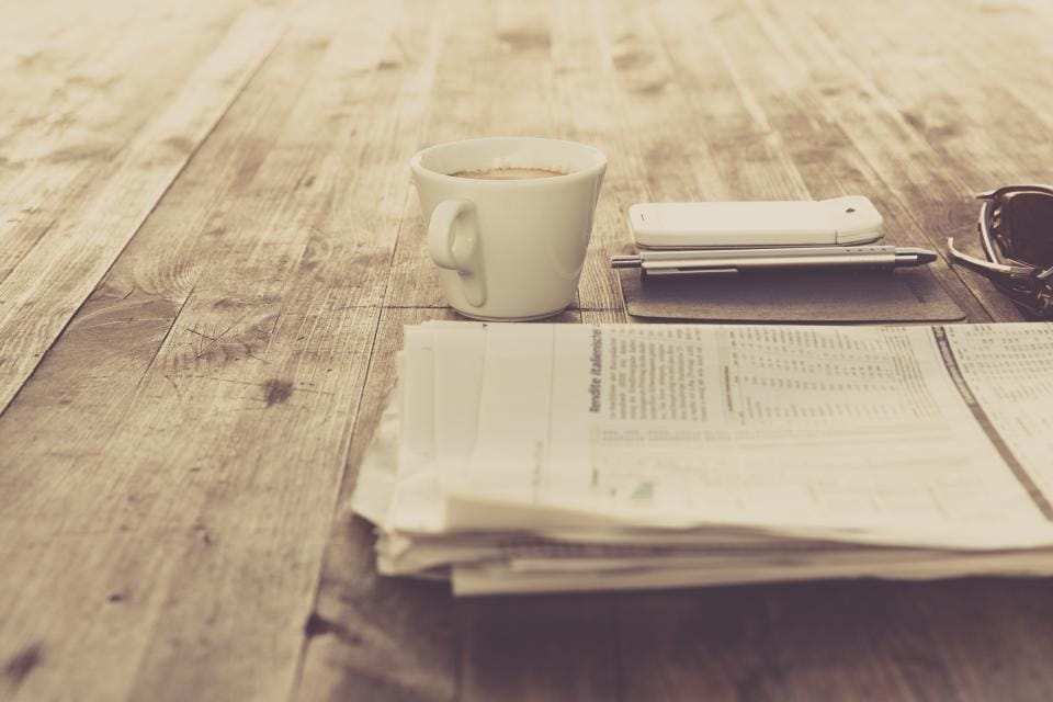 Zeitung und Kaffeetasse auf einem Holztisch