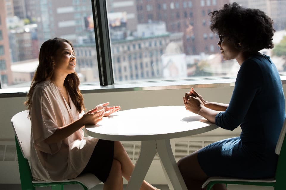 Zwei Frauen im Gespräch an einem Tisch