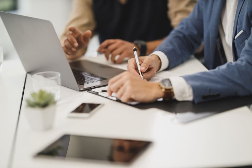 Angestellter notiert Zahlen am Laptop