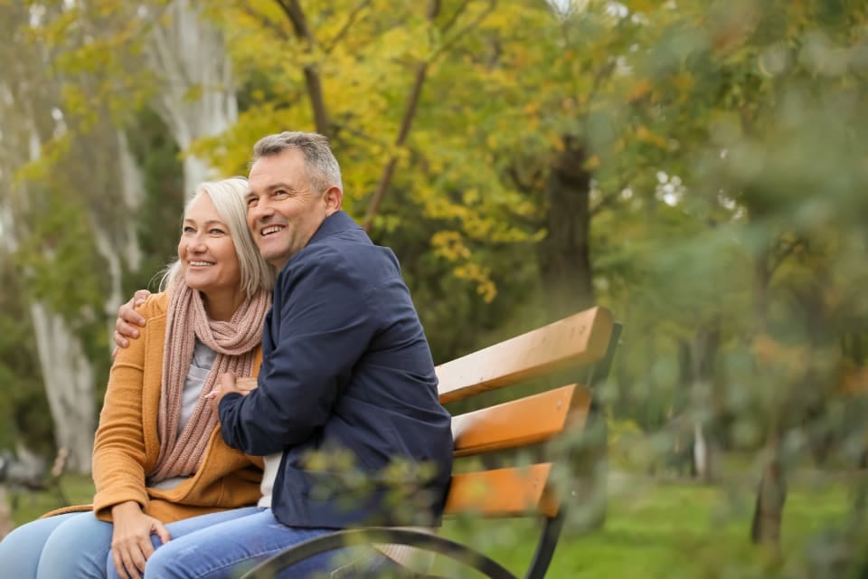 Rentnerpaar auf einer Parkbank im Herbst